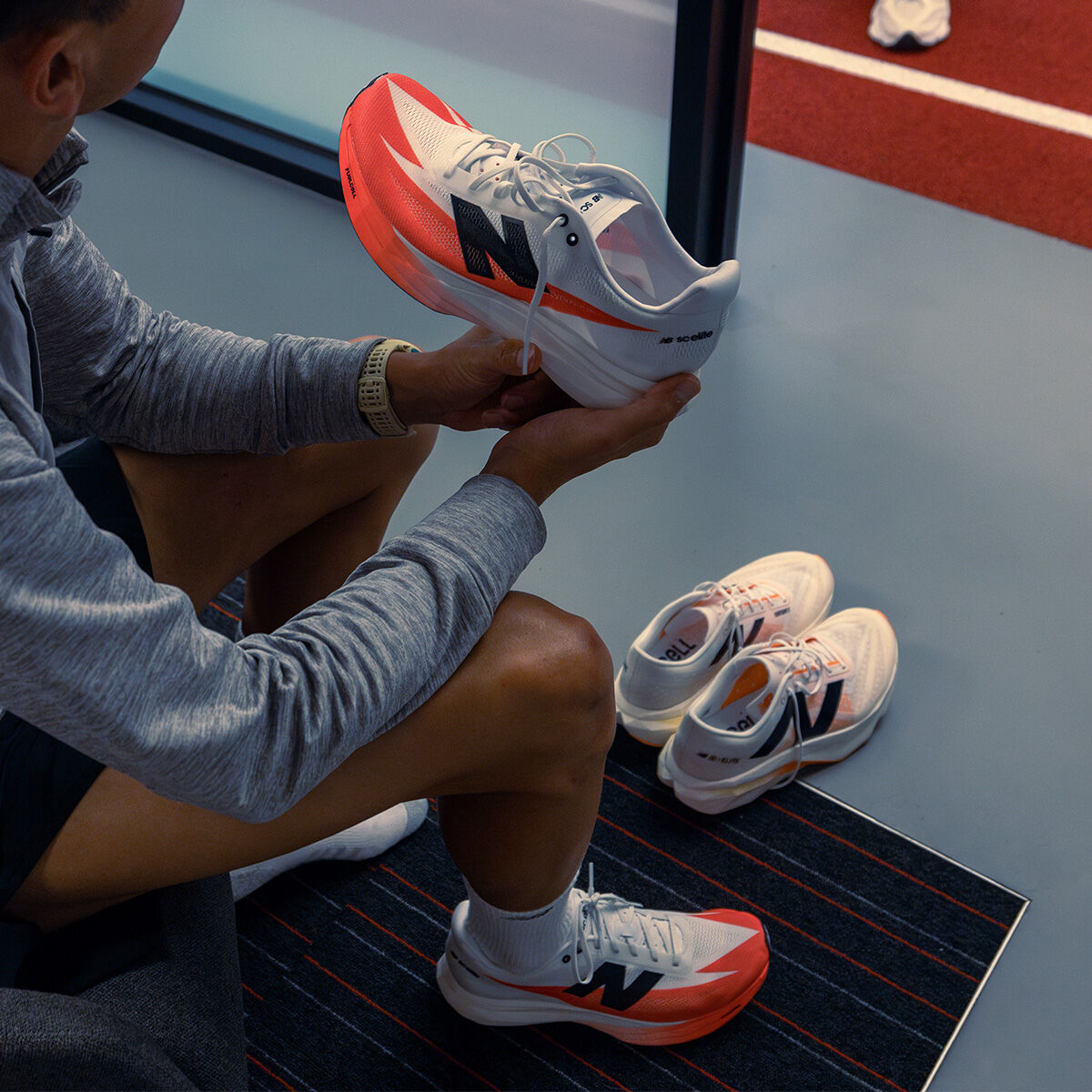 Someone holding a New Balance shoe over a work bench